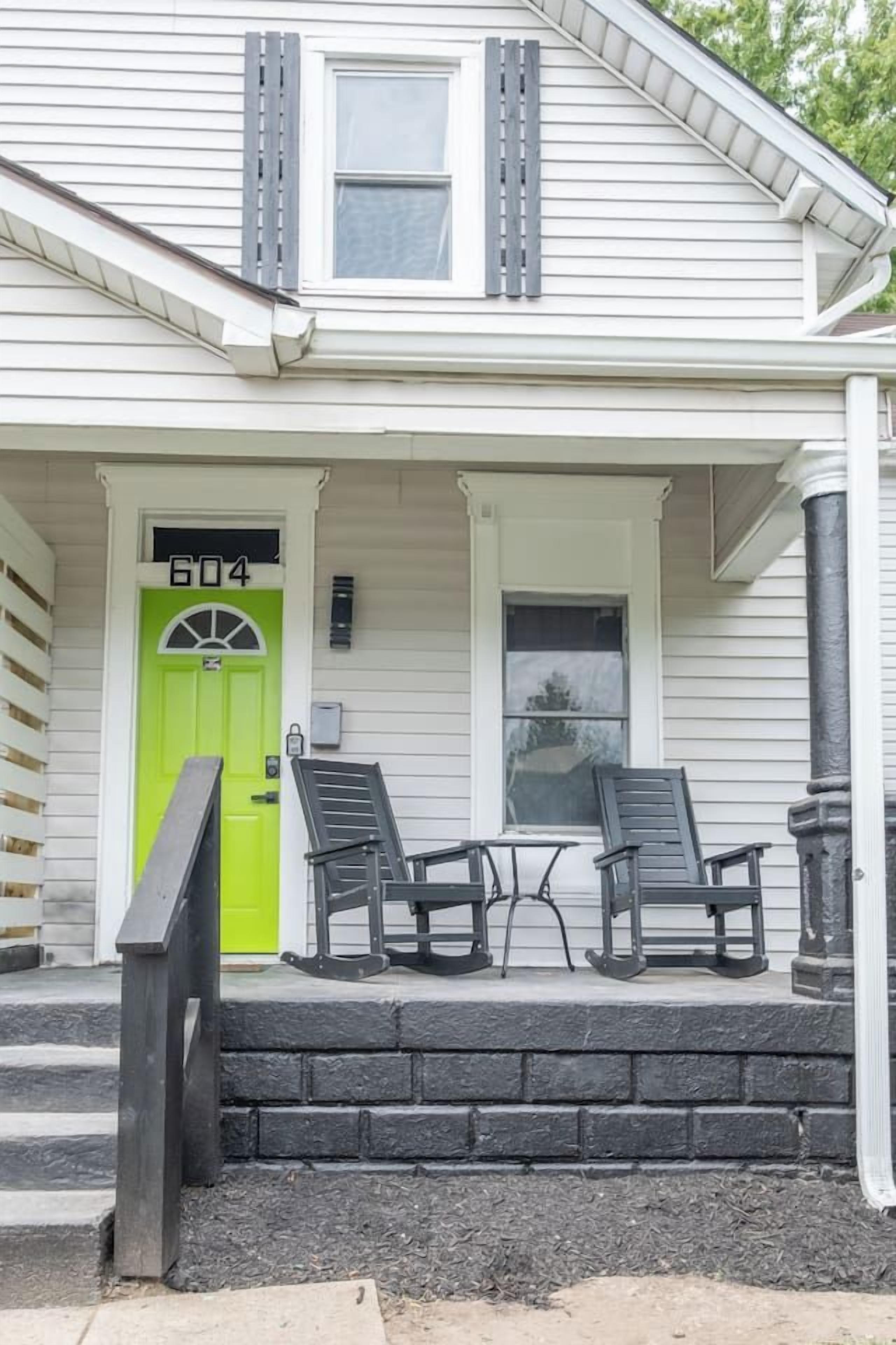 A house with a green door, two chairs on the porch, and a number '604' above the door.