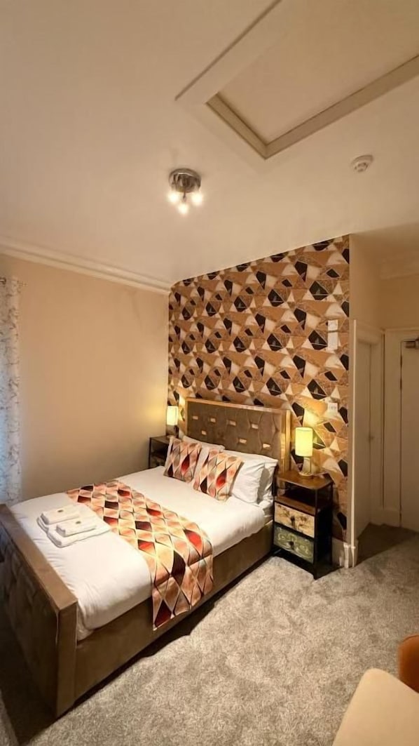 Un dormitorio con cama, mesitas de noche y cabecero estampado.
