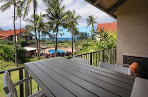 Ein Balkon mit Blick auf einen Pool, Palmen und ein Gebäude mit rotem Dach.