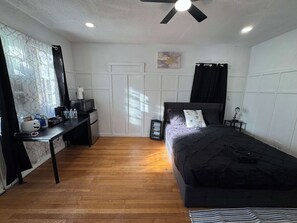 Ein Schlafzimmer mit Bett, Schreibtisch, einer Kaffeestation und einem Kleiderschrank.