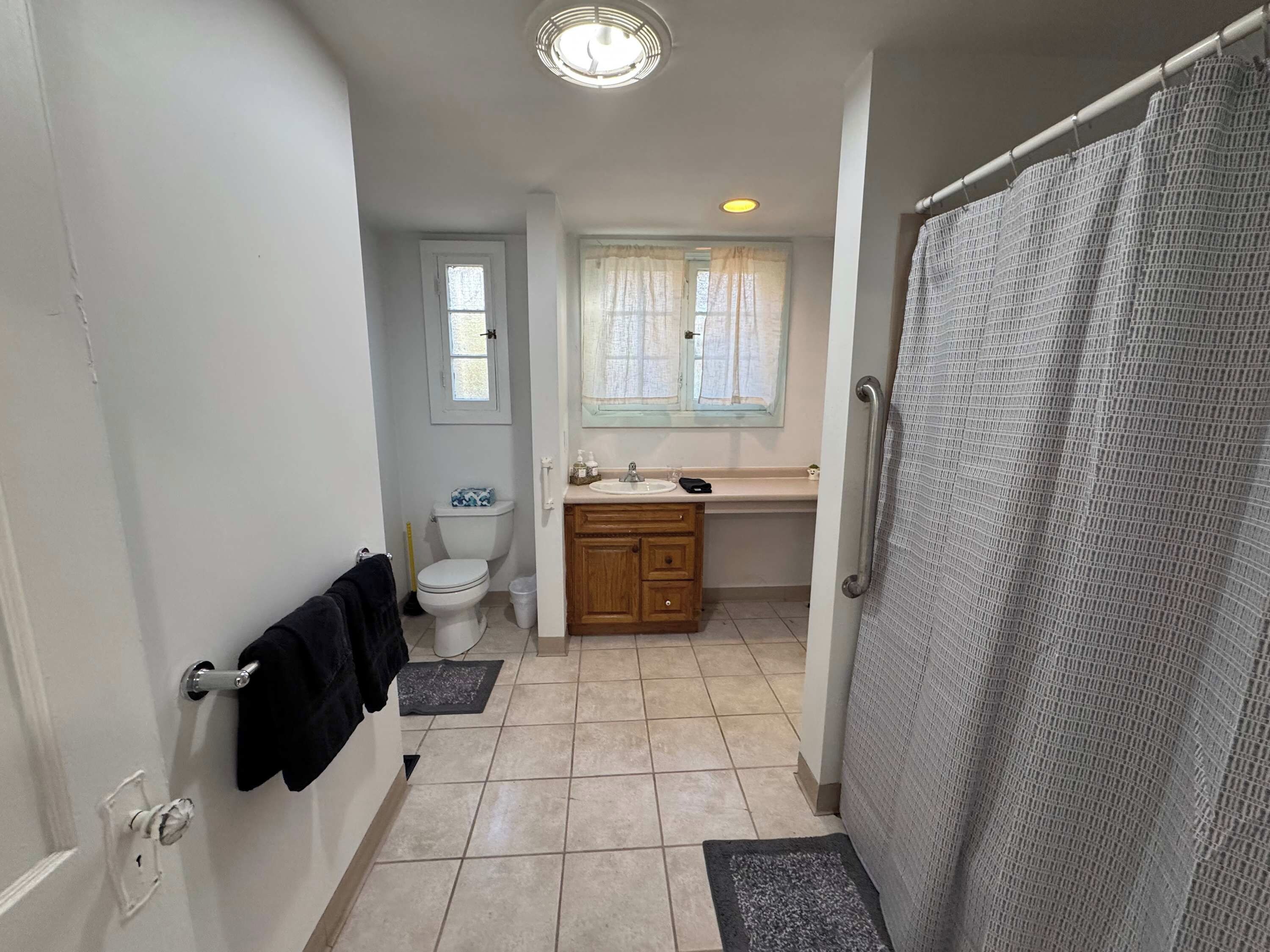 Une salle de bain équipée de toilettes, d’un lavabo et d’un rideau de douche.