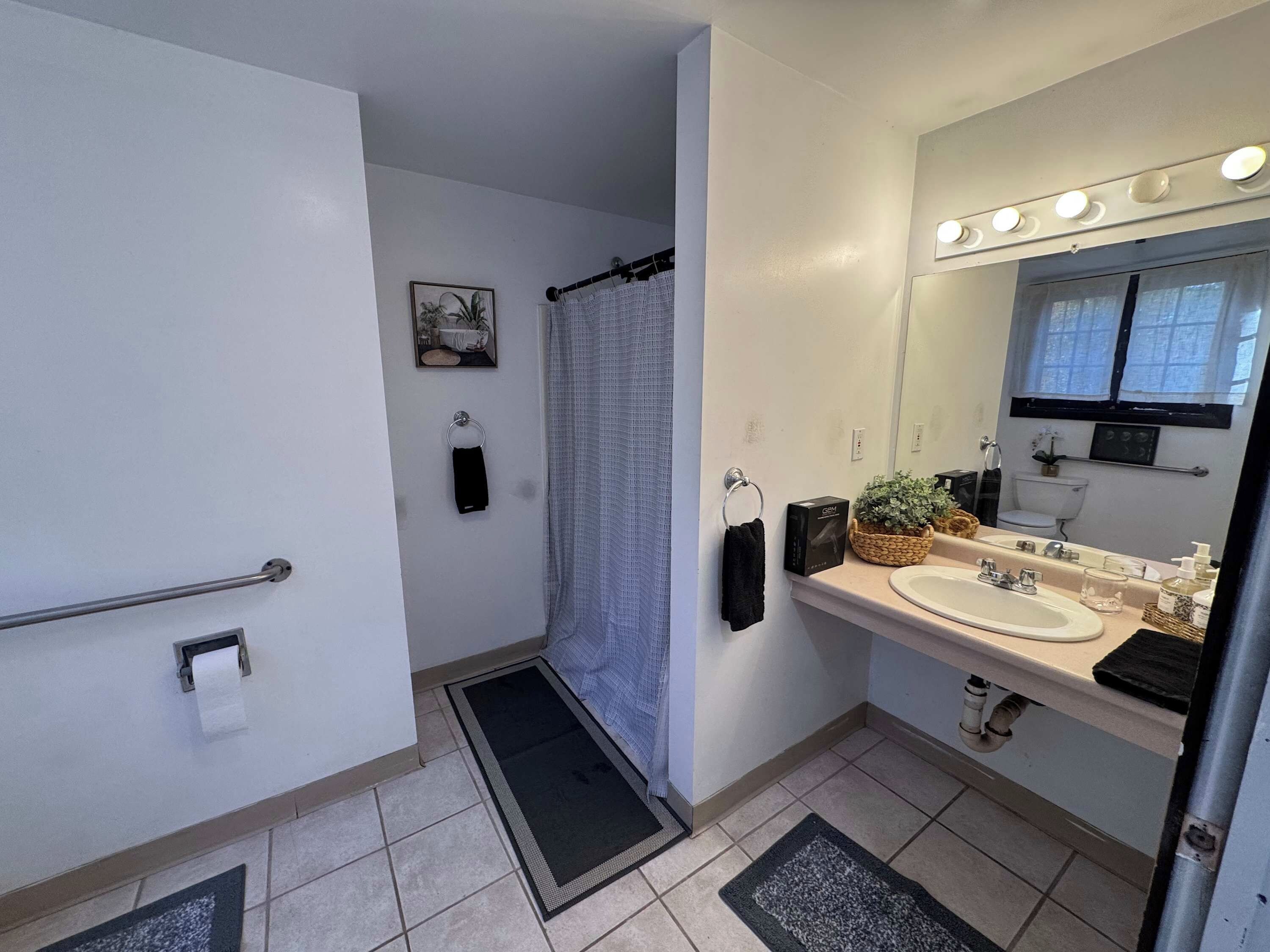 Un bagno con doccia, WC, lavandino e specchio illuminato.