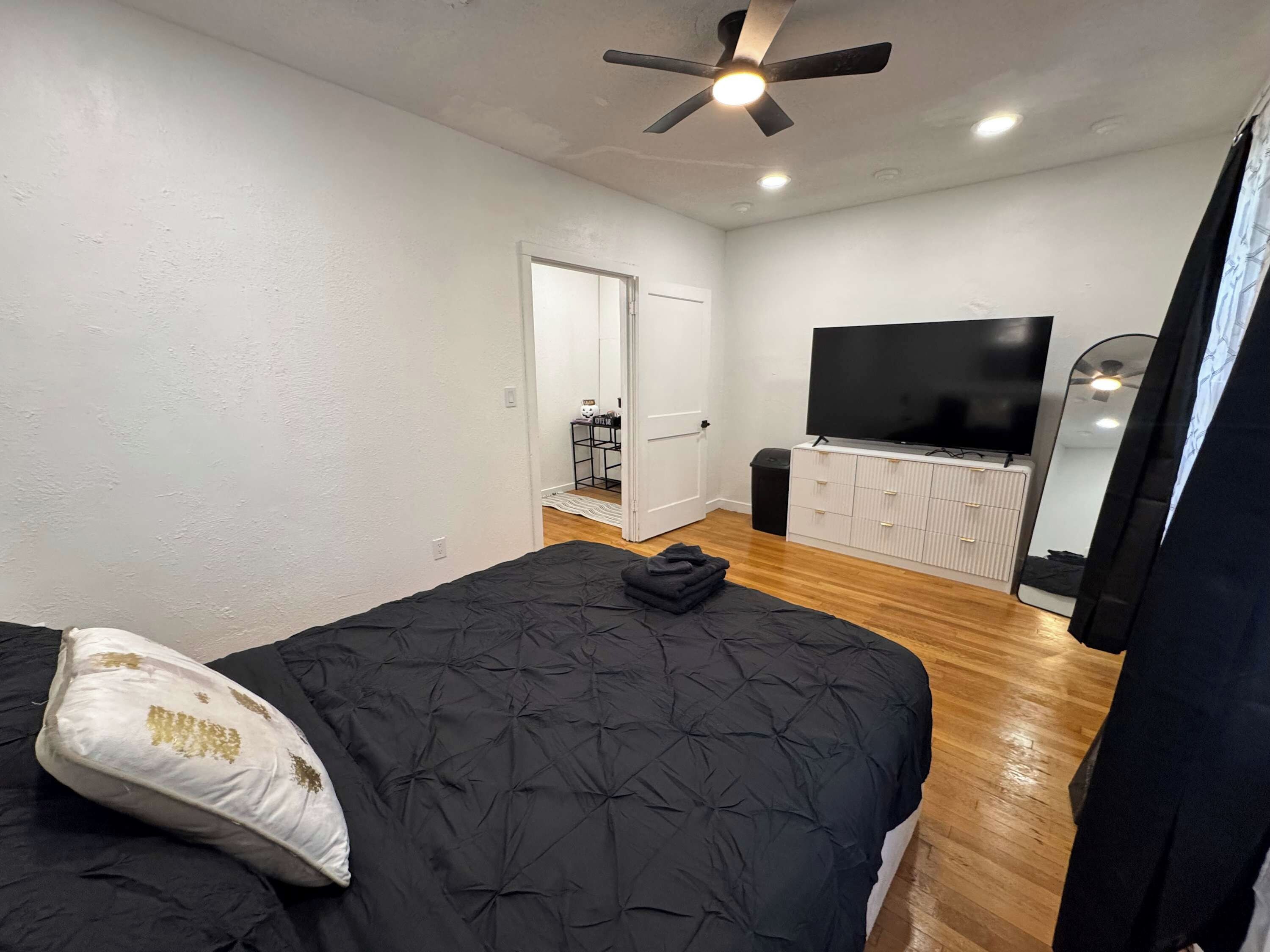 Un dormitorio con cama, ventilador de techo, televisor y armario.