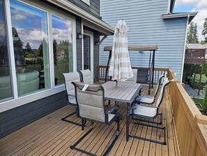 Eine Holzterrasse mit Gartenmöbeln, darunter ein Tisch und Stühle, sowie ein überdachter Sonnenschirm.