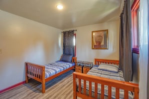 Una habitación con dos camas de madera, una mesita y un cuadro colgado en la pared.