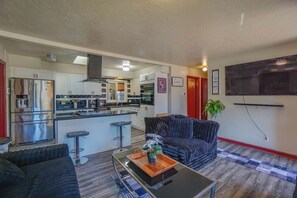 A compact living space with a kitchenette, a dining area with a bar stool, a sofa, and a coffee table.