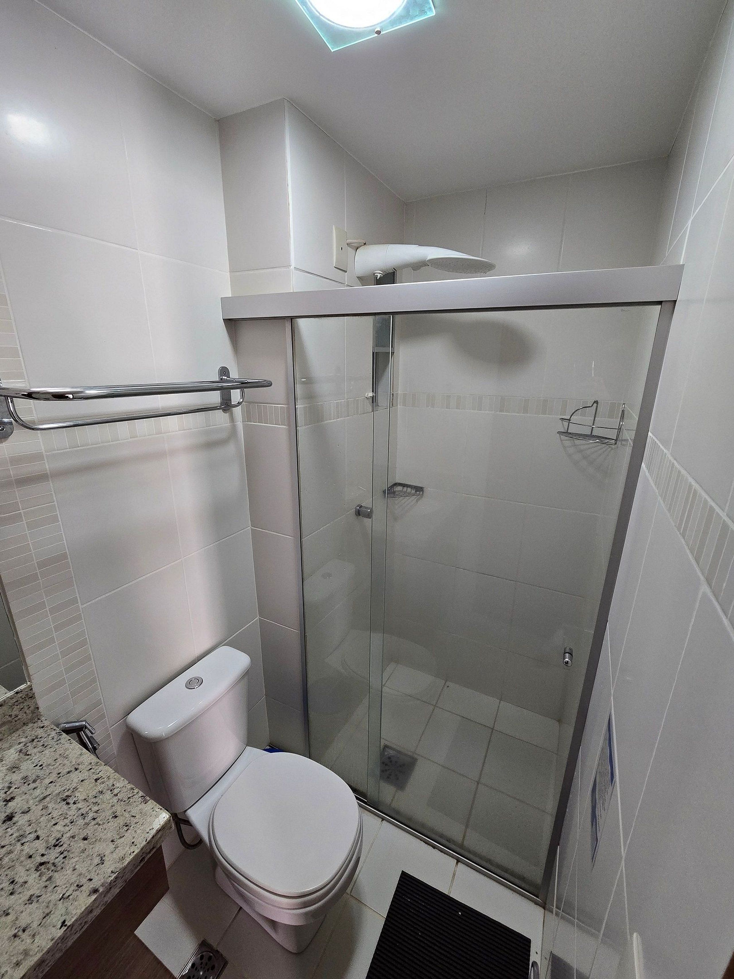 Ein Badezimmer mit Toilette, einer Duschkabine und einem Handtuchhalter.