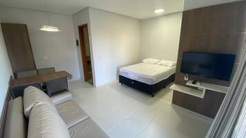 Un dormitorio moderno con cama, televisión y sofá.