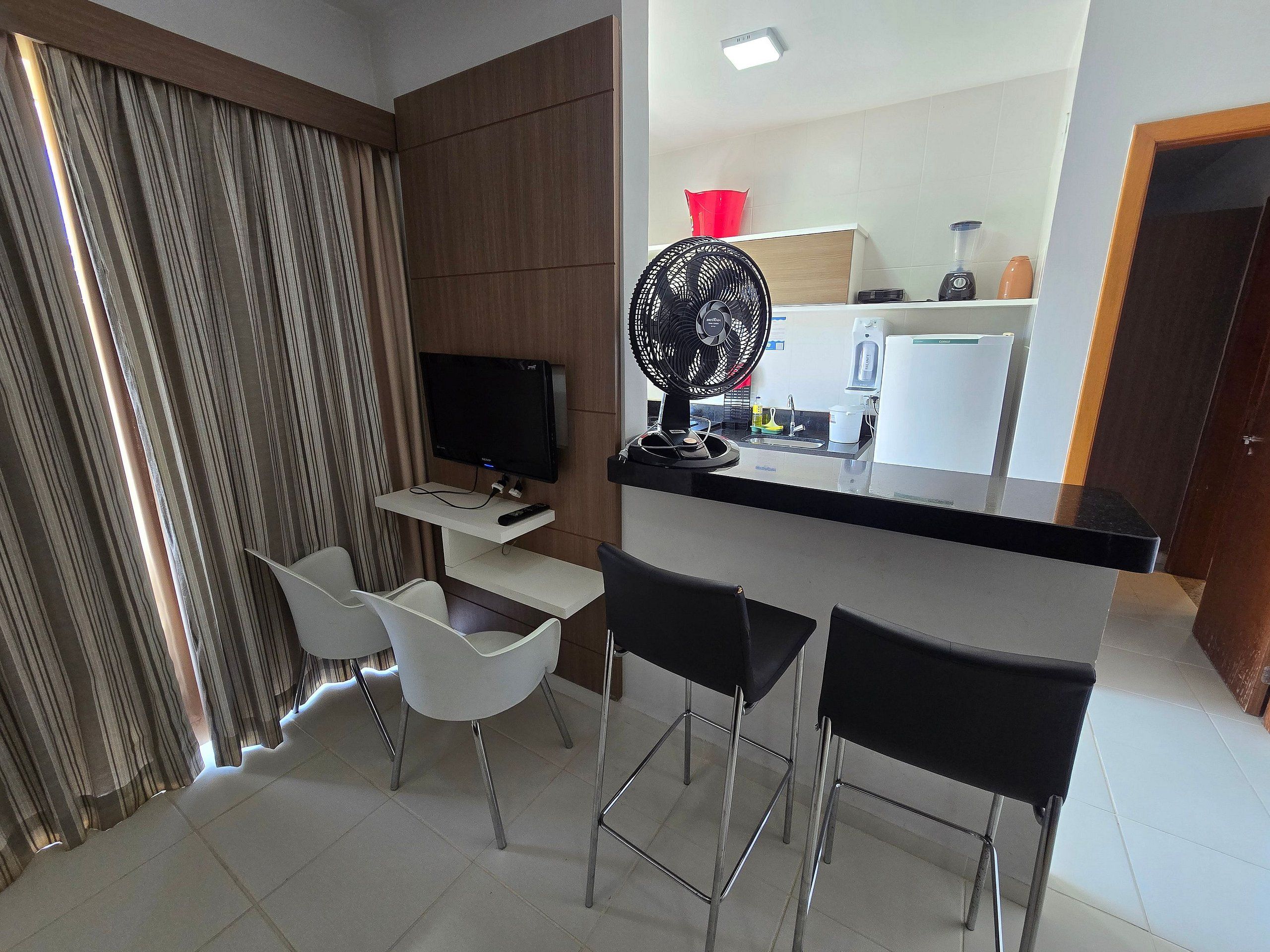 Una cocina moderna con televisor integrado, ventilador y una zona de bar con sillas.