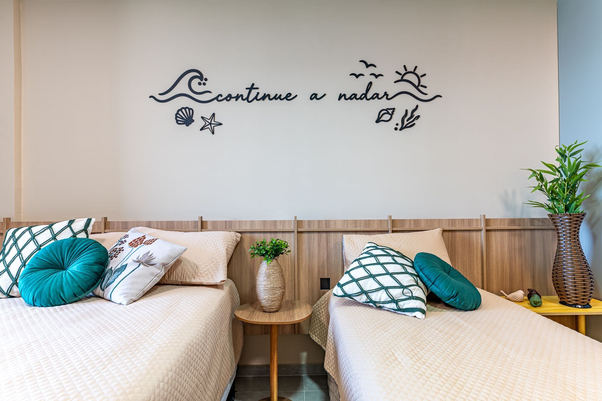 Un dormitorio con dos camas, una decoración en la pared y una planta en maceta.