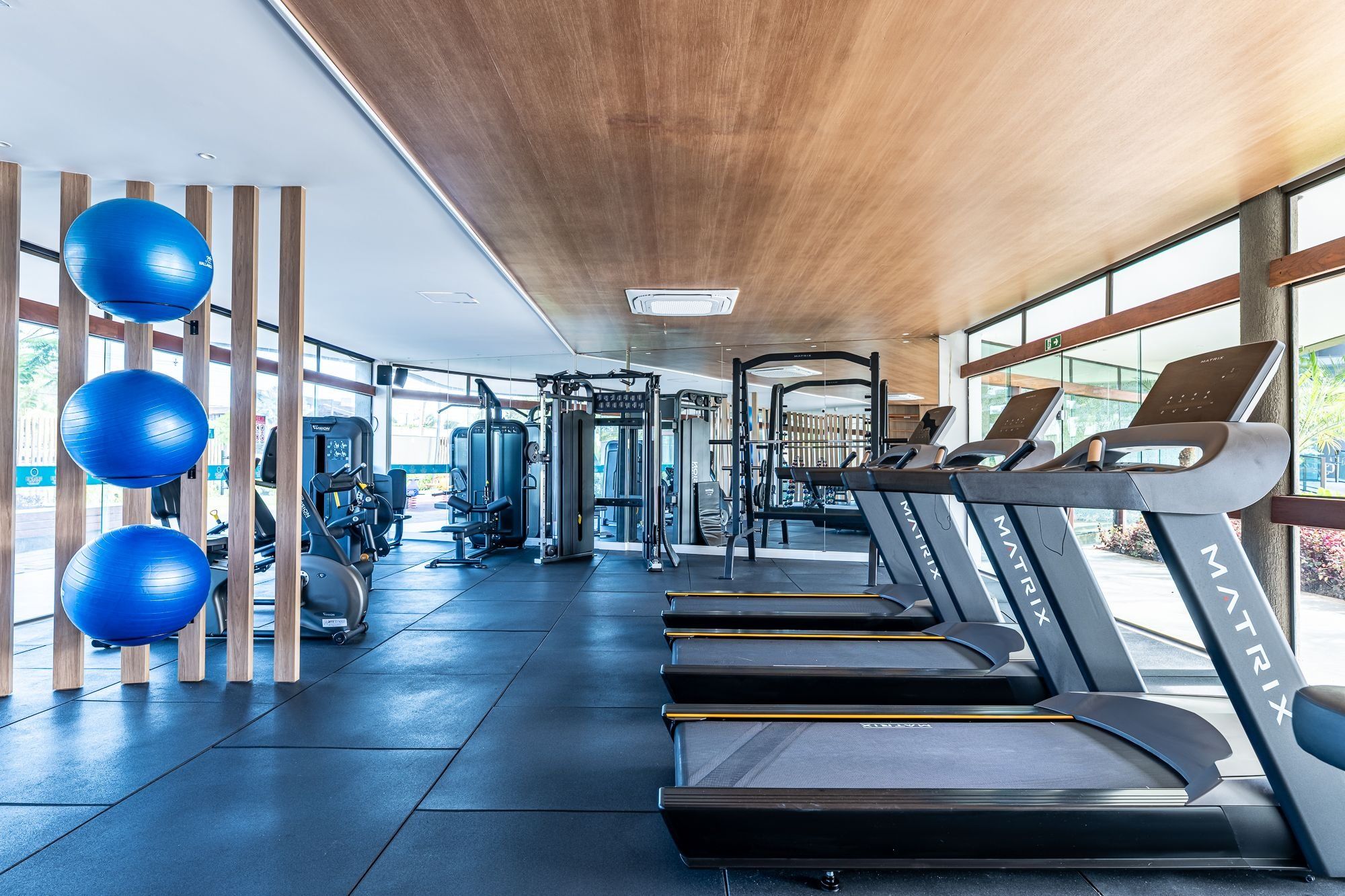 Academia com esteiras, bolas de exercício e máquinas de musculação.