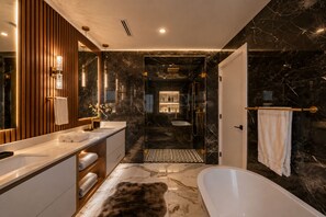Um banheiro moderno com piso de mármore, banheira, chuveiro e toucador com espelho.