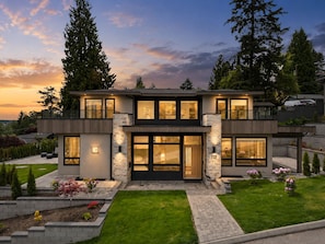 A modern two-story house with a balcony, large windows, and a well-maintained lawn. - North Shore Luxe Villa | Luxury 4BR Near Downtown Vancouver (North Vancouver)