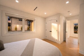 A bedroom with a bed, a window, a wardrobe, and a door leading to another room. - North Shore Luxe Villa | Luxury 4BR Near Downtown Vancouver (North Vancouver)