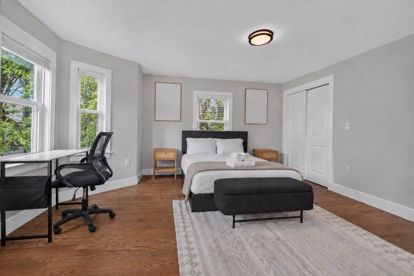 Un dormitorio con cama, escritorio, silla y ventana.