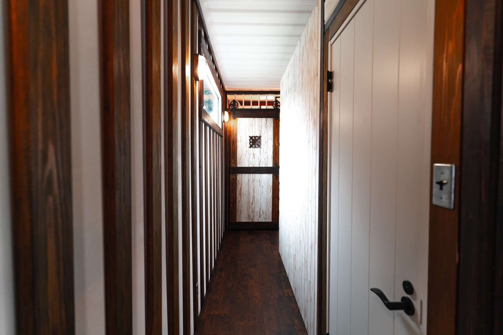 A narrow hallway with wooden paneling and a door with a modern handle.