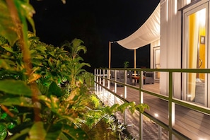 A nighttime view of a modern outdoor deck with a white canopy, surrounded by lush greenery. - Private Oceanfront Escape in Okinawa (Nakijin Village)