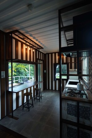 Una cocina moderna con estufa a gas, taburetes de bar y vistas a zonas verdes.