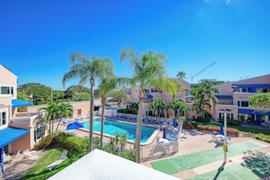 A pool area with lounge chairs and umbrellas, surrounded by palm trees and buildings. - Your Family-Friendly Beach Getaway on Longboat Key (Longboat Key)