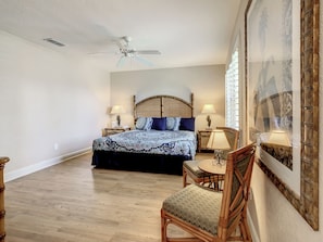 A bedroom with a bed, a chair, a table, a ceiling fan, and a wall with a patterned design. - Anna's Regal Townhome - Comfort & Style (Davenport)