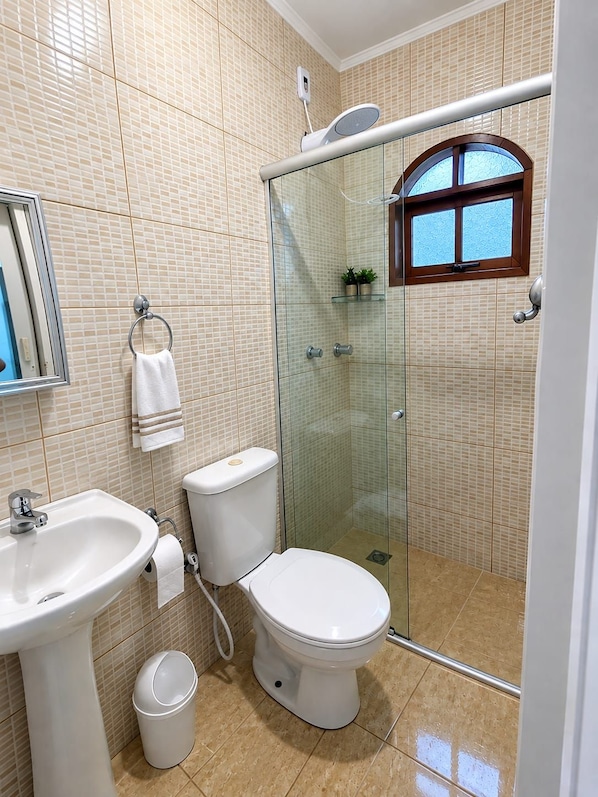 Une salle de bain avec une douche à parois de verre, un lavabo, des toilettes et un miroir.