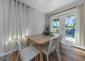 A dining area with a wooden table and white chairs, a potted plant, and a view of a pool through a glass door. - 4BR Austin Home Near Walter E. Long Park (Austin)