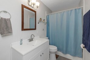 Une salle de bain avec un lavabo blanc, un miroir, des toilettes et un rideau de douche bleu.
