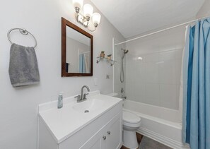 Une salle de bain avec un lavabo blanc, un miroir et une douche.