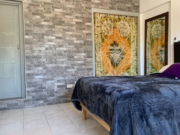 Een slaapkamer met een bed, een bakstenen muur en een decoratief wandkleed.