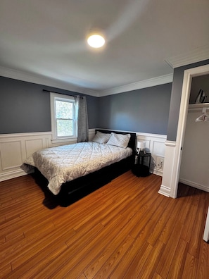Ein Schlafzimmer mit Bett, Fenster, Nachttisch und Kleiderschrank.