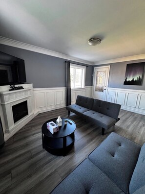 Ein modernes Wohnzimmer mit Kamin, einer Couch, einem Couchtisch und einem Fernseher.