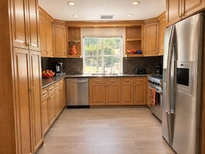 Una cocina moderna con armarios de madera, electrodomésticos de acero inoxidable y un ventanal que proporciona luz natural.