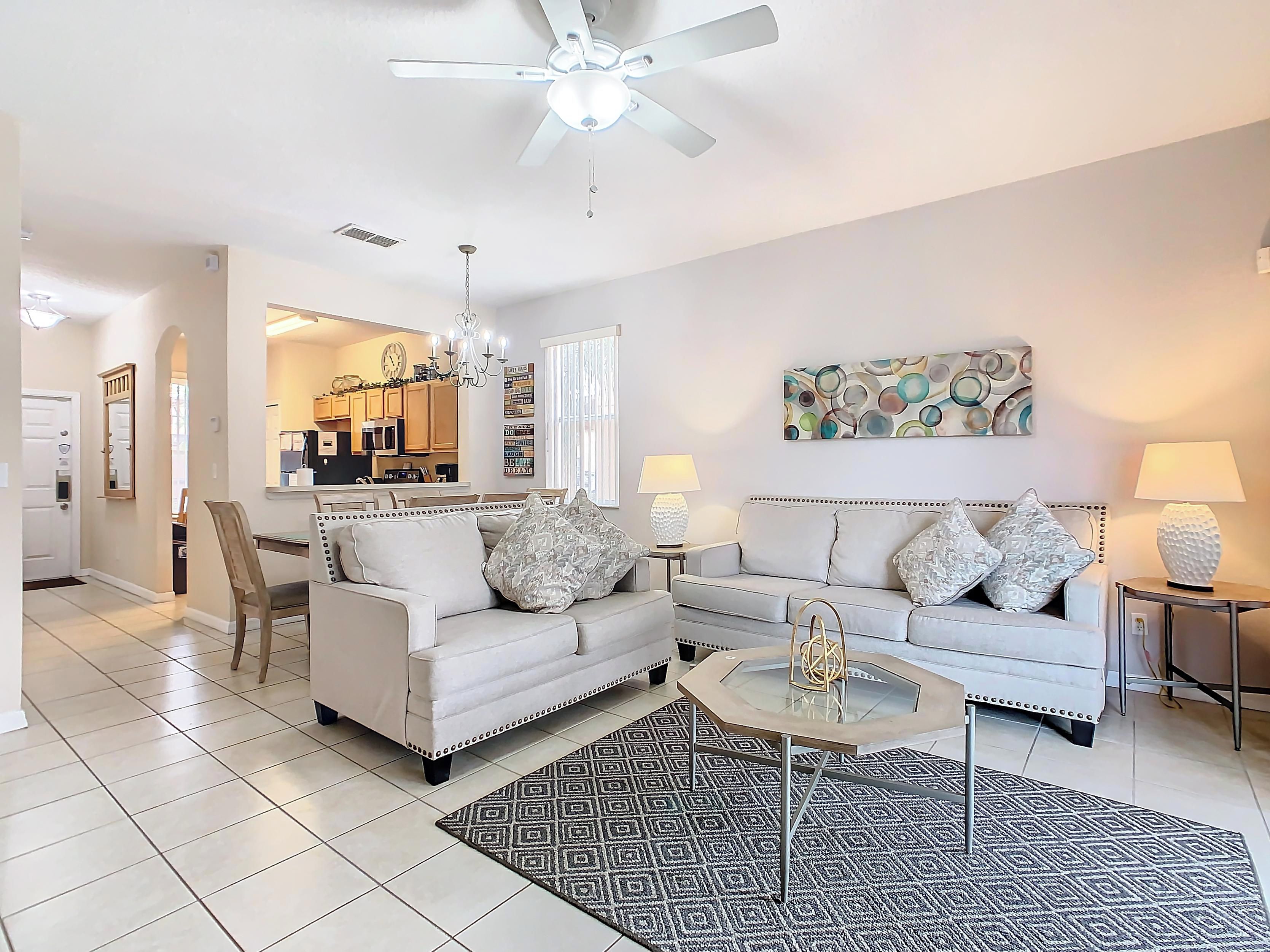 A modern living room with two sofas, a coffee table, and a chandelier.