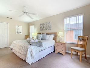 A bedroom with a bed, nightstands, a chair, a ceiling fan, a window, and artwork on the walls. - Family Getaway 4BR Townhome by Old Town (Kissimmee)