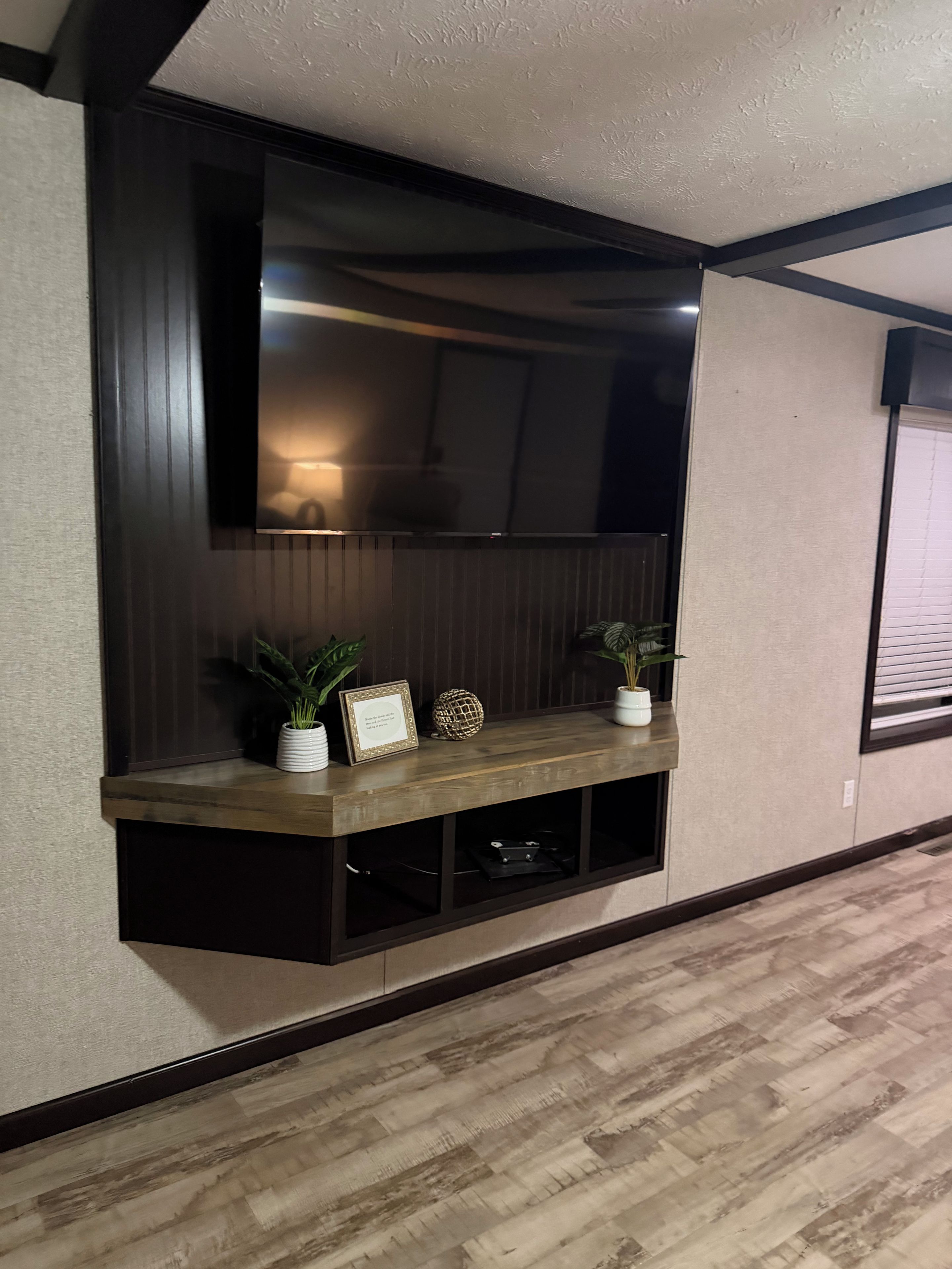 Un meuble de rangement mural conçu pour accueillir un téléviseur, des objets décoratifs et offrir un espace de rangement.