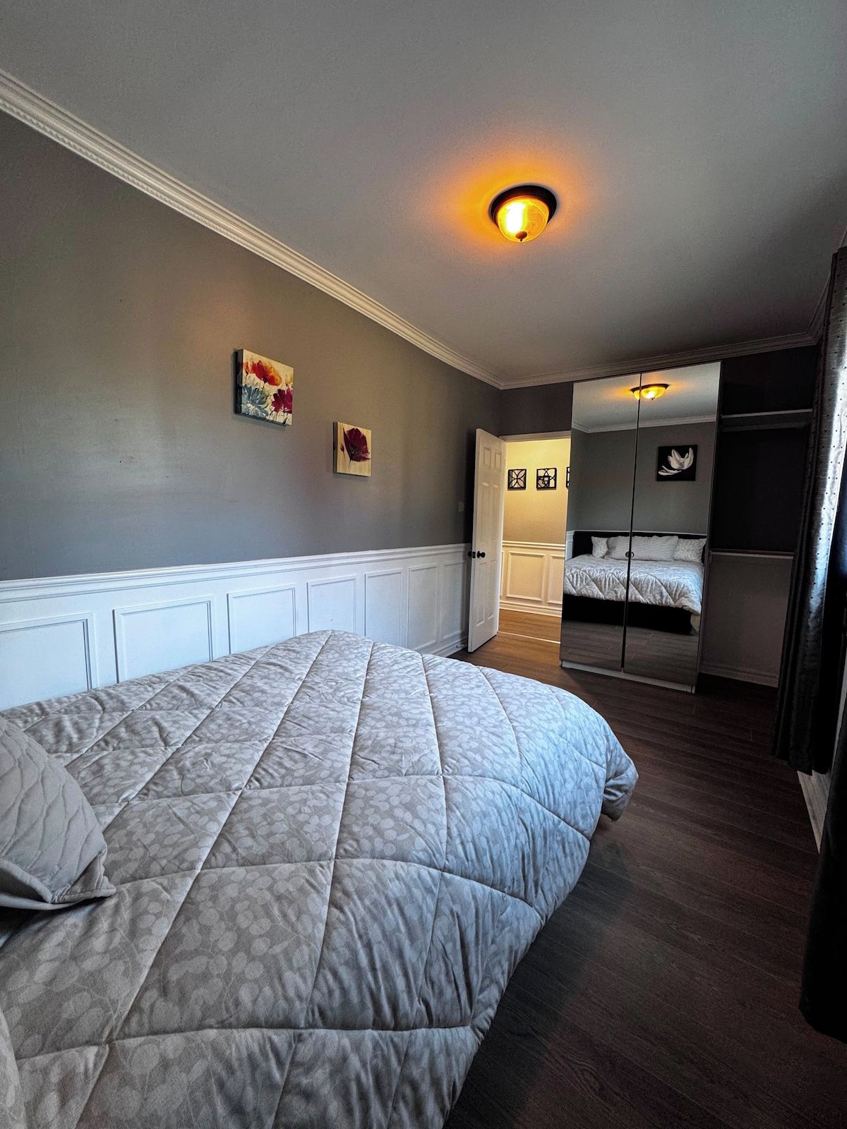 Ein Schlafzimmer mit einem großen Bett, einem kleineren Bett, einem Kleiderschrank und einer Deckenleuchte.