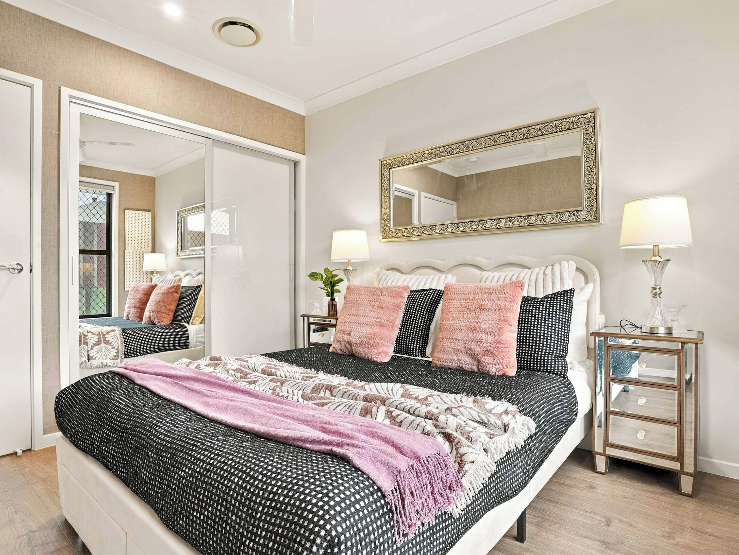 A bedroom with a bed, bedside tables, a mirror, and a door.
