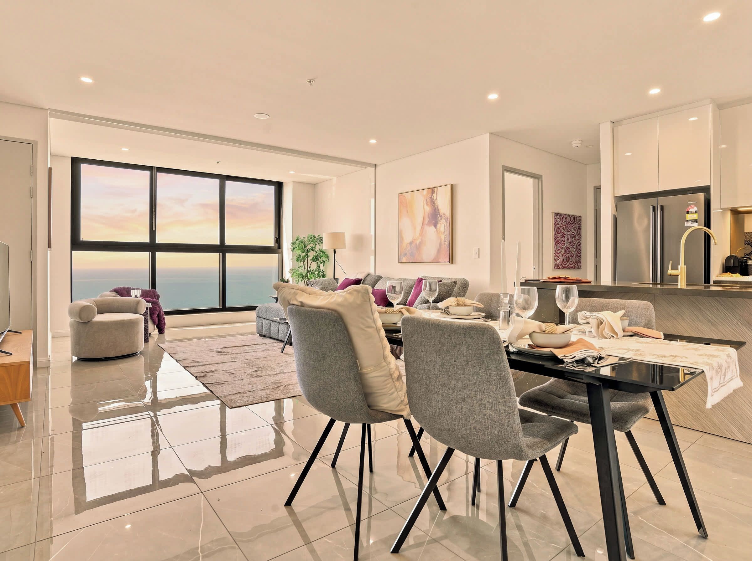 Un salon moderne avec un coin repas, de grandes fenêtres et une vue sur la mer.