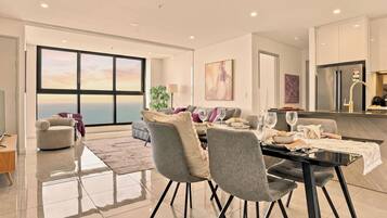 Un salon moderne avec un coin repas, de grandes fenêtres et une vue sur la mer.