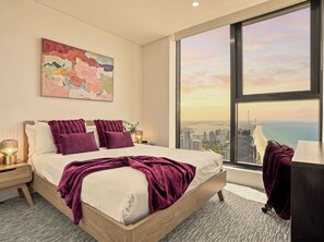 Ein modernes Schlafzimmer mit einem großen Bett, Blick auf die Stadt und einem Gemälde an der Wand.