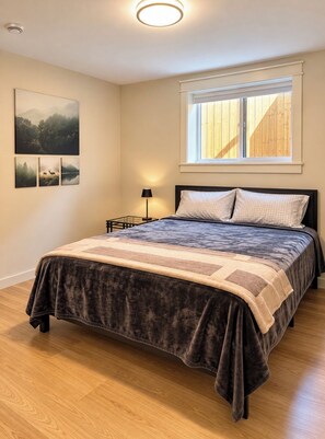 Une chambre à coucher avec un lit, une table de chevet, une lampe et une fenêtre avec des stores.