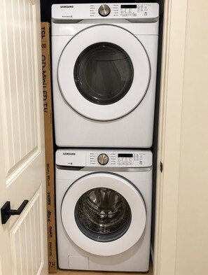 Une machine à laver et un sèche-linge Samsung à chargement frontal, empilés verticalement dans un meuble.
