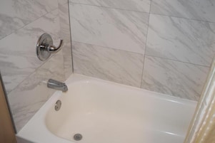 Un baño con bañera, ducha y retrete.