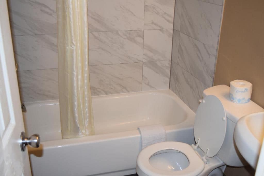 A bathroom with a bathtub, toilet, and a shower curtain.