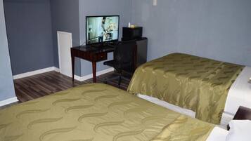 A hotel room with two beds, a desk with a television, and a chair.