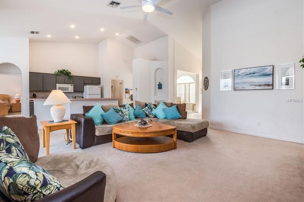 A spacious living area with a sofa set, a coffee table, and a lamp.
