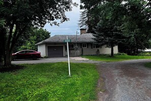 Une maison avec un garage, une allée et une voiture rouge garée devant.