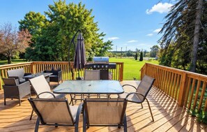 Une terrasse avec une table à plateau en verre, des chaises et un barbecue.