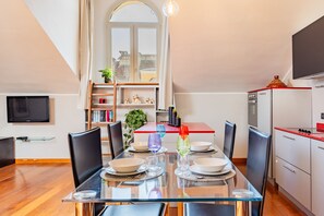 Eine moderne Küche mit Esstisch für vier Personen, einem eingebauten Backofen und einem an der Wand montierten Fernseher.