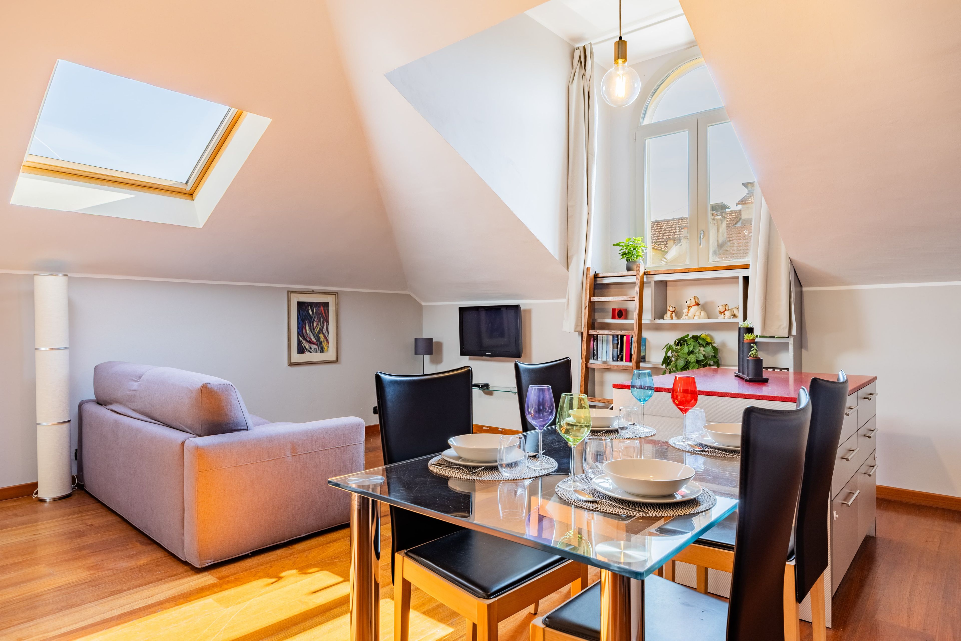 Een modern appartement met een eethoek, een bank, een televisie en een boekenkast.